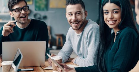 Happy coworkers. Group of young modern people in smart casual wear discussing something and smiling while working in the creative office